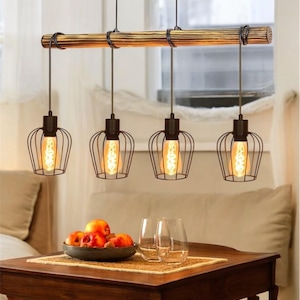 Puede incluir: Una lámpara colgante de cuatro luces con pantallas de jaula de metal negro y una viga de madera rústica. Las luces cuelgan sobre una mesa de madera con dos vasos transparentes y un cuenco de manzanas rojas.