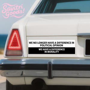 May include: A white bumper sticker on a car with the text "WE NO LONGER HAVE A DIFFERENCE IN POLITICAL OPINION WE HAVE A DIFFERENCE IN MORALITY". The sticker has a black and white design. The car has a red tail light.