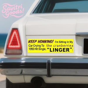Peut inclure: Arrière d'une voiture blanche avec un autocollant. L'autocollant jaune indique : "KEEP HONKING! I'm Sitting In My Car Crying To the cranberries 1993 Hit Single, 'LINGER'!" La voiture a un feu arrière rouge et un pare-chocs noir.