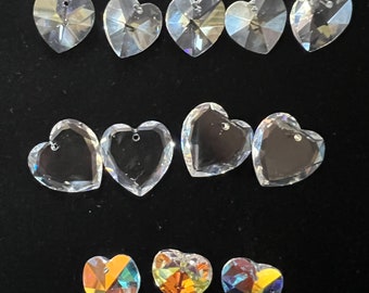 May include: A collection of clear crystal heart-shaped charms with a hole at the top for hanging. Some of the charms have iridescent rainbow colors.