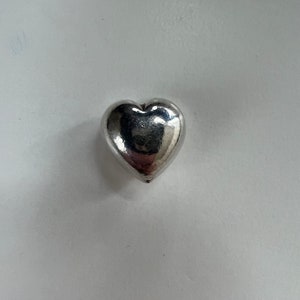 May include: A silver heart-shaped charm.
