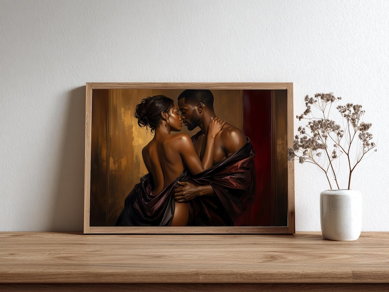 May include: A framed wall art print depicting a couple in an intimate embrace, draped in dark fabric against a warm, golden-brown background. The artwork features rich tones of deep red and bronze, capturing a moment of connection between two figures.