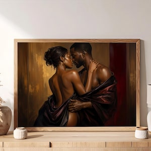 May include: A framed wall art print depicting a couple in an intimate embrace. The figures have dark skin tones and are draped in deep burgundy and black fabric. The background features warm, golden-brown tones with vertical architectural lines.