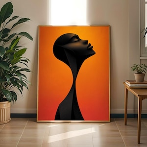 May include: A framed art print depicting a black silhouette of a face looking upwards. The background is a gradient of orange and red. The frame is light brown. The artwork is displayed in a room with plants and wooden furniture, creating a warm atmosphere.