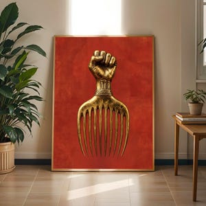 Peut inclure: Une impression d'art mural rectangulaire représentant un peigne afro en or métallique avec un manche en forme de poing, centré sur un fond orange brûlé texturé. L'œuvre est encadrée par un cadre doré fin, montrant un poing levé.