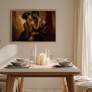 May include: A rectangular wall art print featuring a romantic scene of a couple embracing, draped in dark fabric against a warm gold and deep red background. The artwork is displayed in a light wood frame above a dining table with candles.