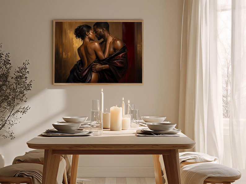 May include: A rectangular wall art print featuring a romantic scene of a couple embracing, draped in dark fabric against a warm gold and deep red background. The artwork is displayed in a light wood frame above a dining table with candles.