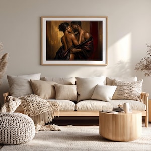 May include: A framed wall art print depicting a couple in an intimate embrace, wrapped in dark fabric against a warm, golden-brown background. The artwork features deep shadows and highlights, showcasing the figures in a close, romantic pose.