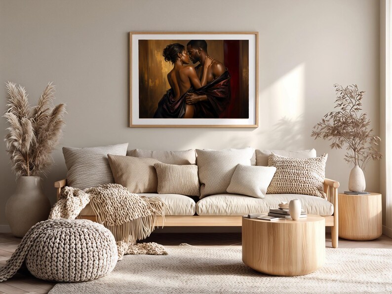 May include: A framed wall art print depicting a couple in an intimate embrace, wrapped in dark fabric against a warm, golden-brown background. The artwork features deep shadows and highlights, showcasing the figures in a close, romantic pose.