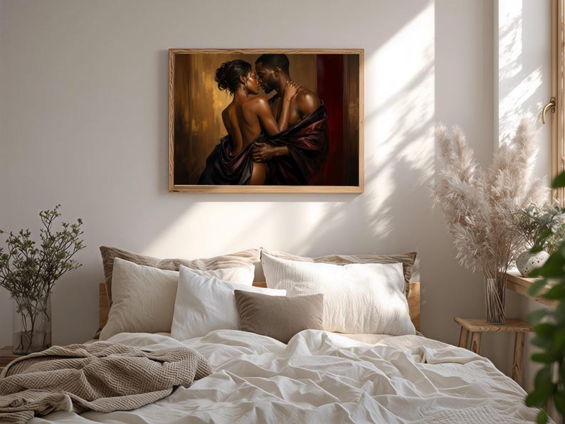 May include: A framed wall art print depicting a couple in an intimate embrace, draped in dark fabric against a warm, golden-brown and deep red background. The artwork features rich lighting and shadows, highlighting the figures in a close pose.