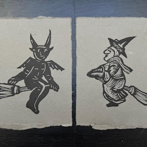 Peut inclure: Deux illustrations en noir et blanc de personnages chevauchant des balais. La figure de gauche est un diable avec des cornes et une queue. La figure de droite est une sorcière avec un chapeau pointu.