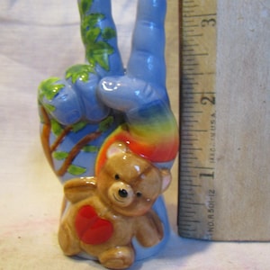 Mano con signo de la paz de bebé arcoíris con forma de oso de peluche de WhimsiClay. Prototipo exclusivo de Amy Lacombe, más pin floral gratis