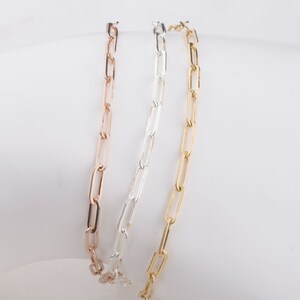 May include: Three gold chain bracelets, one in rose gold, one in silver, and one in yellow gold. The chains are all the same style, with a simple, linked design.