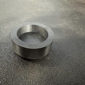 May include: A black plastic ring with a circular opening in the center. The ring is smooth and has a slightly textured surface.