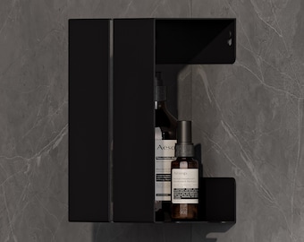Puede incluir: Estantería negra montada en la pared con dos compartimentos. La estantería contiene dos botellas marrones con etiquetas blancas. La unidad está montada en una pared gris con diseño de mármol. La estantería tiene un diseño moderno y minimalista.