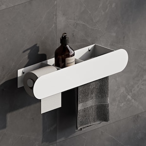 Könnte beinhalten: Ein weißer Wand-Badezimmer-Organizer mit einer horizontalen Ablage und einer abgerundeten Frontblende. Die Einheit hält links eine Rolle Toilettenpapier, eine braune Braunglasflasche mit Aesop-Etikett und ein darunter hängendes graues Handtuch.