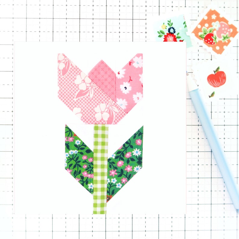 May include: A pink and green fabric tulip flower appliqu&eacute; with a white background. The tulip is made of different patterned fabrics, including pink gingham, pink floral, and green floral.