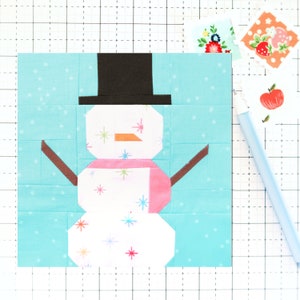 May include: A white snowman with a black top hat, orange nose, and pink scarf on a light blue background. The snowman has a white background with small colorful stars.