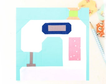 May include: A white sewing machine with a blue top and a pink fabric piece. The machine is on a light blue background.