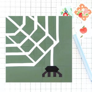 Könnte beinhalten: Ein grüner und weißer Quiltblock mit geometrischem Muster. Der Block hat eine schwarz-weiß gestreifte Basis.