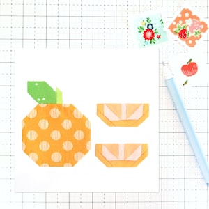 May include: A fabric applique of an orange with two orange slices. The orange is orange with white stripes and orange polka dots. The orange slices are orange with pink and white accents.