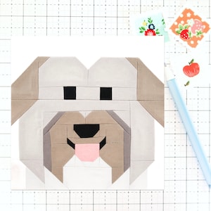 Può includere: Un blocco di trapunta patchwork che rappresenta un cane con uno schema di colori grigio chiaro, marrone e bianco. Il cane ha la lingua rosa che sporge.