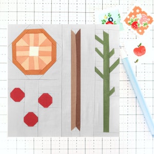 May include: A patchwork quilt block with a brown tree trunk, green branches, three red octagons, and a peach-colored octagon with a white center.