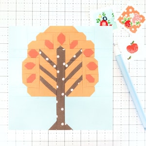 Op de afbeelding: Een lichtblauw vierkant van stof met een bruine en oranje boom-applicatie. De boom heeft een bruine stam met witte stippen en oranje bladeren met perzikkleurige accenten.