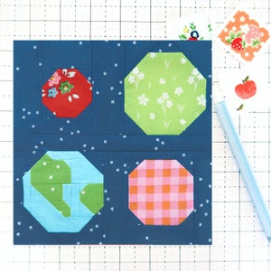 Pode incluir: Um fundo de tecido azul com quatro patches de tecido octogonais. Os patches são vermelhos com flores brancas, verdes com flores brancas, azuis e verdes, e xadrez rosa e laranja.