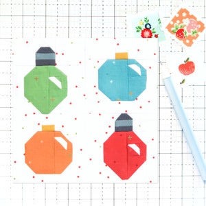 May include: Four fabric ornaments in different colors and patterns. The ornaments are green, blue, orange, and red. They are all in the shape of a Christmas tree ornament and have a white star on them.