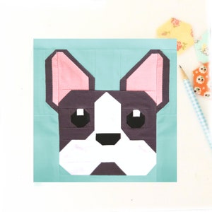 May include: A block pattern of a French bulldog with pink ears, black eyes, and a black nose on a light blue background.