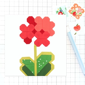 May include: A red and green fabric flower with a yellow stem. The flower is made of squares and is a simple design.