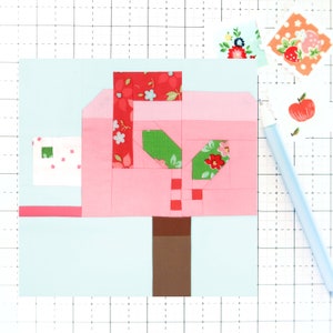 May include: A pink fabric mailbox with a green and red floral pattern. The mailbox has a brown post and a white envelope with a green square on it.