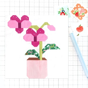 May include: A pink and green fabric flower in a pink pot. The flower has two large pink petals and a green stem with leaves.