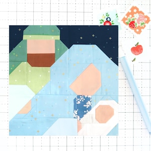 May include: A patchwork quilt block depicting the nativity scene. The block is made of various fabrics in shades of blue, green, pink, and brown. The figures of Mary, Joseph, and the baby Jesus are represented in the block.