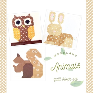 May include: A set of three quilt blocks featuring woodland animals. The blocks are made of brown, tan, and white fabric with a variety of patterns. The animals include an owl, a bunny, and a squirrel. The text "Woodland Animals quilt block set" is printed below the blocks.