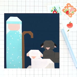 May include: A blue and white patterned fabric figure of a shepherd with a brown staff, standing next to two white sheep and a black sheep on a dark blue background.