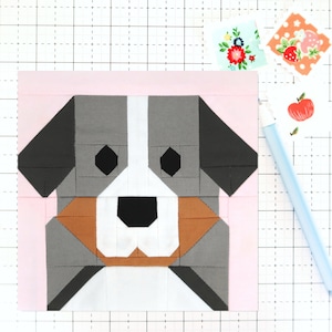 Op de afbeelding: Een patchwork quiltblok met een Berner Sennenhond in een wit, grijs en bruin kleurenschema. Het gezicht van de hond is gemaakt van geometrische vormen.