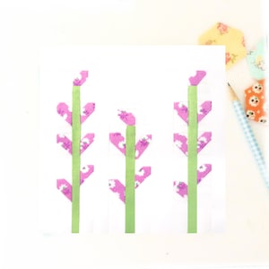 May include: Three pink and green fabric flowers with white floral print on a white background.