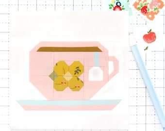 May include: A pink teacup and saucer with a yellow floral design. The teacup has a brown rim and a white tea bag hanging from the side.