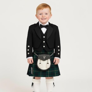 May include: A young boy wearing a traditional Scottish kilt outfit. The outfit features a black jacket, waistcoat, and bow tie, along with a green and black plaid kilt. A sporran, white socks, and black shoes complete the ensemble.