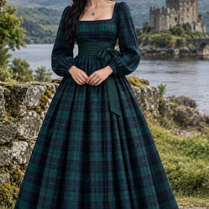 May include: A floor-length dress featuring a dark green and navy blue plaid pattern, a square neckline, and long sleeves. The garment includes a solid dark green fabric sash tied at the waist, creating a gathered, full-length skirt silhouette.