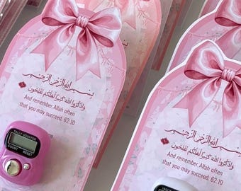 May include: Pink and white prayer counter cards with a digital tally counter. Each card features a pink bow, floral accents, and Arabic text. The counter is available in pink and white.