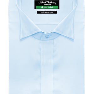 Puede incluir: Camisa azul claro con cuello clásico y puños abotonados. La camisa tiene cierre de botones en la parte delantera y una etiqueta que dice "John Clothier LONDON Green Label 100% Cotton."