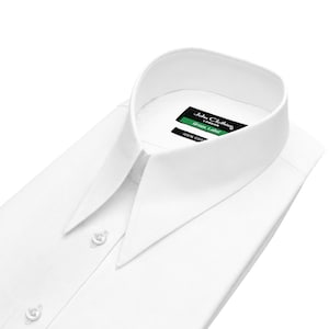 Könnte beinhalten: Ein weißes Langarm-Hemd mit einem spitzen Kragen und einer Knopfleiste auf der Vorderseite. Das eingenähte Etikett am Kragen zeigt den Text John Clothier London, Green Label und 100% Cotton in weißer und grüner Schrift auf schwarzem Grund.
