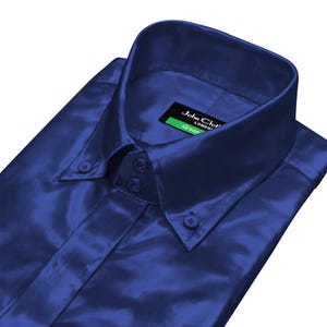Puede incluir: Primer plano de una camisa azul marino con botones y un acabado brillante. La camisa tiene un cuello clásico y botones. Una etiqueta con el texto "John Cloth London Green" es visible.