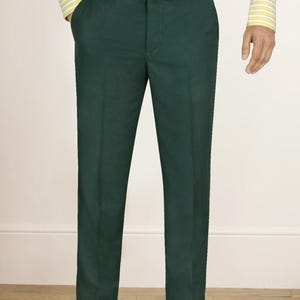 May include: Bottle green trousers paired with a patterned belt and a yellow and white striped shirt. The trousers have a classic cut. The belt features a multi-colored design. The outfit is completed with brown leather shoes.