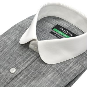 May include: A gray button-down shirt with a white collar. The shirt has a textured appearance and a single button is visible. The label reads "John Clothier London Green Label 100% COT".