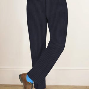 May include: Navy blue pinstripe trousers with a matching belt. The trousers are paired with brown leather dress shoes. A light blue and white striped shirt is visible above the trousers.