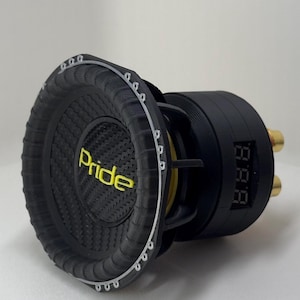 Pode incluir: Subwoofer preto com a palavra "Pride" em amarelo. O alto-falante tem uma superfície texturizada e um display digital. Os conectores dourados são visíveis na lateral.